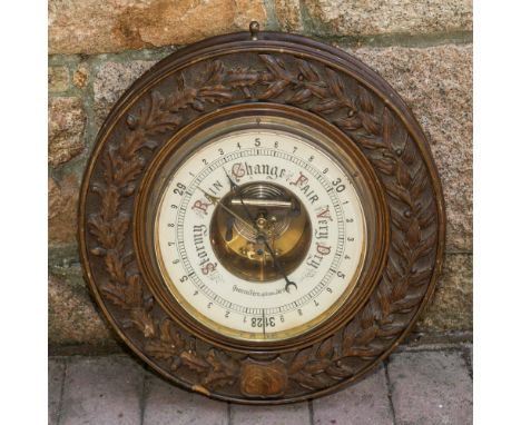 A large circular Channel Islands Aneroid Barometer by Quenouillère Optician, Jersey, the carved wooden case carved with a ban