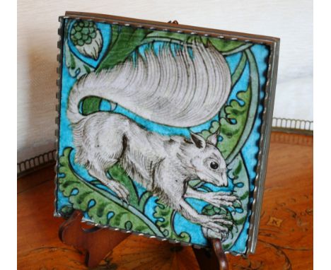 A William de Morgan tile, 19th century, with majolica style decoration of a black and white squirrel amidst green foliage, on