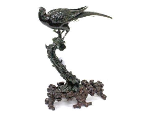 A SPINACH JADE CARVING OF A GOLDEN PHEASANT seated on a branch, 30cm high together with a carved wooden stand 