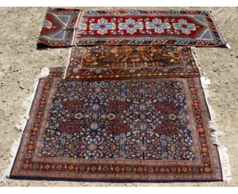 A 20TH CENTURY REPRODUCTION FOLIATE PATTERNED RUG on a blue and red ground, each end with fringed tassels, 125cm x 167cm toge