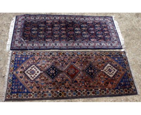 TWO 20TH CENTURY CARPET RUNNERS, both with geometric patterns on a blue and peach ground, with fringed tassel edges and folia