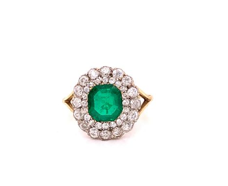 AN ANTIQUE EMERALD AND DIAMOND CLUSTER RING. THE EMERALD CENTRE SURROUNDED BY A DOUBLE HALO OF OLD CUT DIAMONDS, ON A SPLIT S