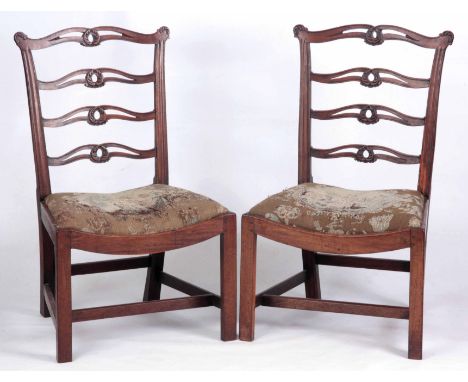 A PAIR OF MID 18TH CENTURY MAHOGANY SIDE CHAIRS with carved ladder backs and dished drop in tapestry seats; standing on squar