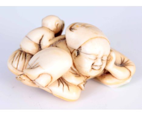 A 19TH CENTURY JAPANESE CARVED IVORY NETSUKE of a sleeping man with a monkey stealing fruit from his basket 2.5cm high 5.5cm 