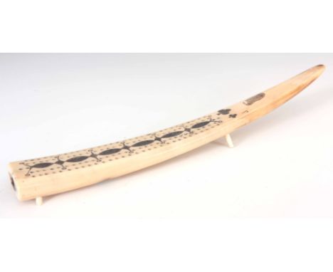 A 19TH CENTURY SCRIMSHAW WALRUS TUSK CRIBBAGE BOARD decorated with a Walrus, clubs and a repeated pattern, dated 1841 standin