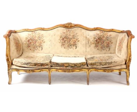 A 19TH CENTURY LOUIS XV STYLE GILT GESSO SERPENTINE SHAPED THREE SEATER SETTEE with flower carved scrolled frame, upholstered