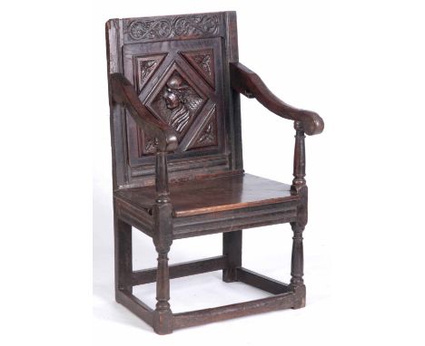 A 17th CENTURY JOINED OAK WAINSCOT CHAIR with a scrolled leaf-carved top rail above a carved lozenge portrait panelled back w