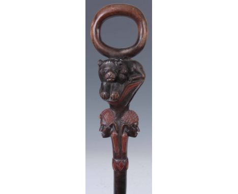 AN UNUSUAL ETHNIC COLOURED AND STAINED HARDWOOD STICK with ring handle above a carved lions head mask and reversed male and f