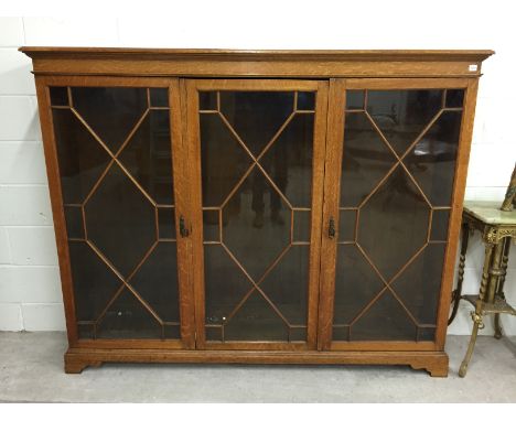 Triple Door Oak Bookcase, raised on bracket feet. 190cm long  48 cm wide 152cm high.