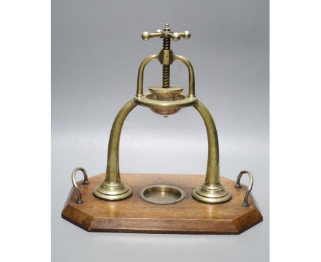 An Edwardian brass lemon squeezer on an oak plinth