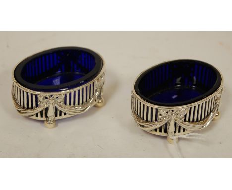 A pair of early 20th century pierced silver open salts, with swag and bow decoration, and blue glass liners, by William Hutto