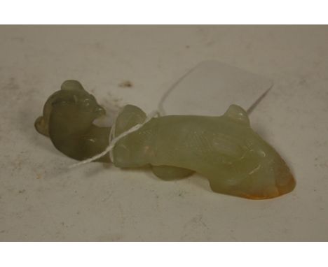 An early 20th century Chinese carved and polished celadon jade belt hook, in the form of a stylised dragon, with some russet 