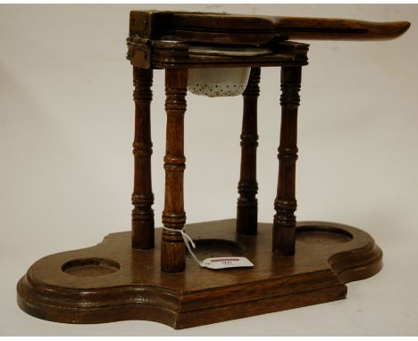 An early 20th century oak and brass mounted table top fruit press, the hinged handle above a pierced enamel bowl bearing a la