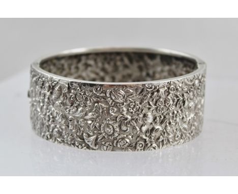 A HEAVILY EMBOSSED DECORATIVE SILVER BANGLE, 24g. 