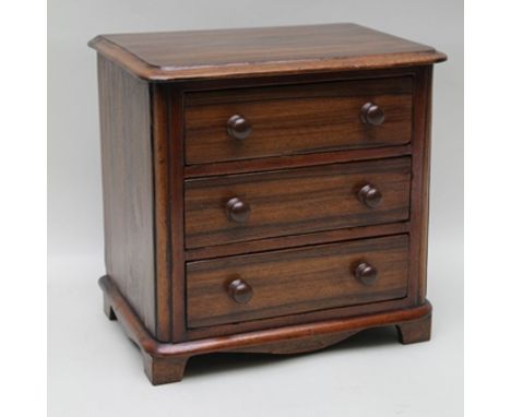 A 19TH CENTURY ROSEWOOD APPRENTICE CHEST, having three drawers with turned knob handles, raised on bracket feet, 28.5cm wide 