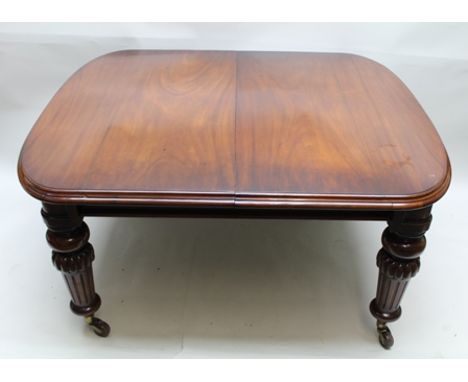 A VICTORIAN MAHOGANY WIND-OUT DINING TABLE, raised on turned and fluted supports with castors, complete with three leaves, 12