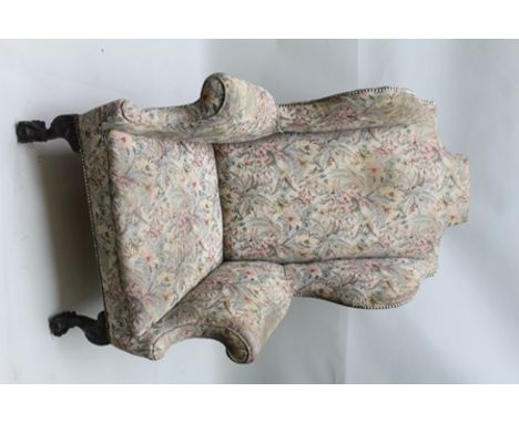 A GEORGIAN DESIGN WING BACK EASY CHAIR, upholstered in machine work tapestry, raised on carved cabriole ball and claw fore fe