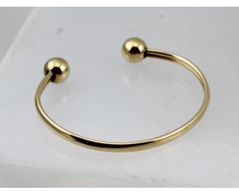 A BANGLE, having ball ends, believed to be 9ct gold, 8g. 