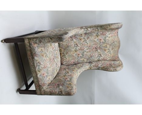 A GEORGIAN DESIGN WING BACK EASY CHAIR, upholstered in machine work tapestry, having mahogany supports with brass fore castor