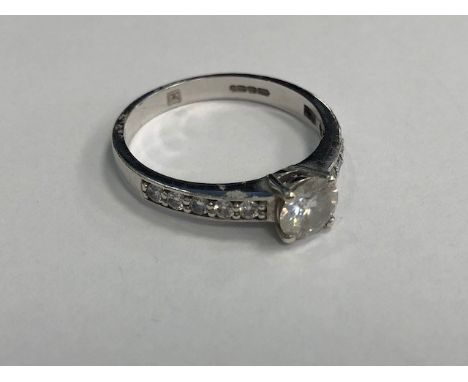 MOISSANITE SINGLE STONE RING, the round stone 7mm in diameter, with further round stones on each shoulder, in nine carat gold