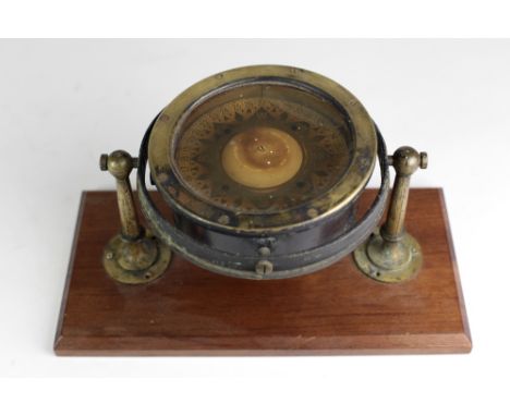 An early 20th Century brass Ships Compass, with rotating dial mounted on a wooden platform base. (1)