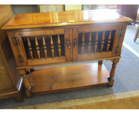 A reproduction walnut finished food cabinet with twin spindle panelled doors, over a shelf, on turned black legs 