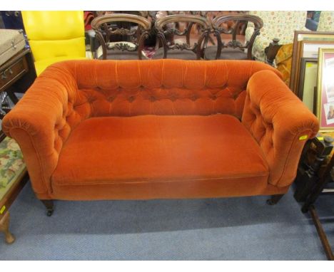 An early 20th century drop end Chesterfield sofa, part button upholstered in a rust coloured dralon, on mahogany legs 