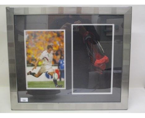 An Adidas rugby boot, signed by Jonny Wilkinson with a photograph of him taking a kick, in 2003 World Cup, mounted in a box f