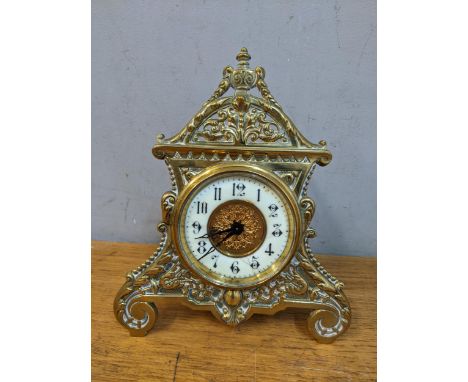 A late 19th century French brass cased clock having an enamel chapter ring, scroll shaped feet and an easel back, 23cm hLocat