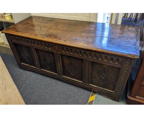 A late 17th/early 18th century oak coffer having a hinged top above four panel front with carved diamond lozenges, 66cm x 158