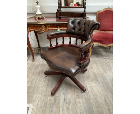 A brown leather button back captain’s chair on swivel base 