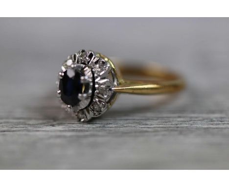 Sapphire and diamond 18ct yellow gold and white gold set cluster ring, the central blue-black oval mixed cut sapphire measuri