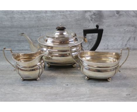 Harrods George V three piece silver tea service comprising teapot, milk jug and twin handled sugar bowl, of plain form raised