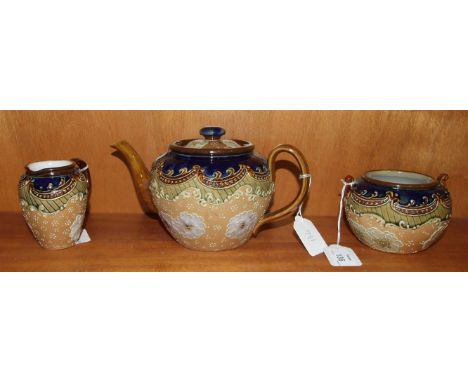 A Royal Doulton stoneware three-piece tea service decorated with flowers on a pale ground, within green and blue borders, com