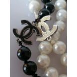 A Chanel black and white bead necklace with six black and white logo links, 160 cm