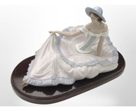 A Nao figure of a seated lady wearing a dress, No. 1265, on wooden plinth, overall 38cm wide.