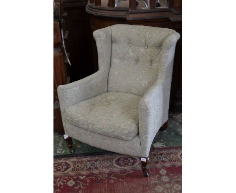 A late Victorian mahogany button upholstered wing back armchair, squab cushion, French scroll legs, ceramic casters