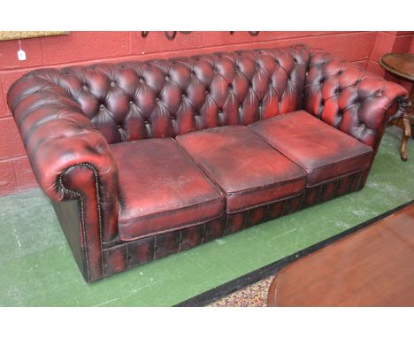 An ox-blood leather three seat Chesterfield sofa.