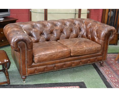 A brown leather Chesterfield button upholstered two seat sofa.