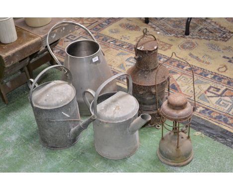 Two vintage galvanized watering cans; a stainless milk pail; ship's lantern; a Tilley lamp (5)