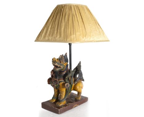 A TABLE LAMP  in the form of a carved polychrome painted Balinese temple lion on a rectangular plinth base, 28cm long x 63cm 