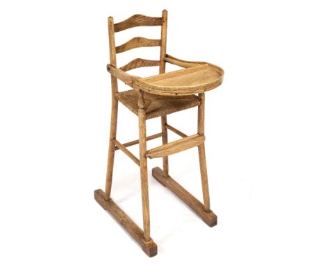 A COTSWOLD SCHOOL ASH AND ELM CHILD'S HIGH CHAIR with ladder back, rush seat, folding table 40cm wide x 54cm deep x 99cm high