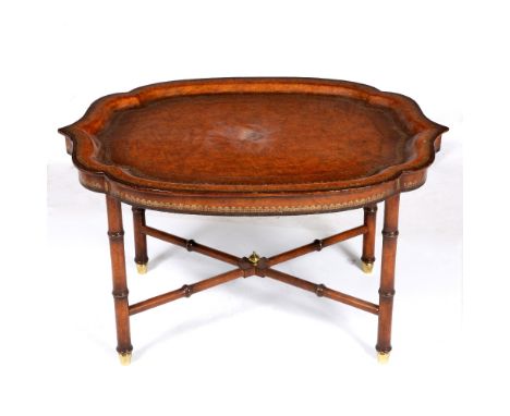 A SERPENTINE SHAPED TOOLED LEATHER COVERED TRAY on a matching stand with ring turned legs united by an 'X' stretcher 80cm wid