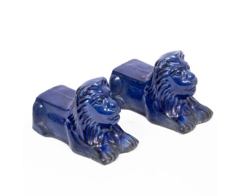 A PAIR OF BLUE GLAZED TERRACOTTA SASH WINDOW STOPS in the form of resting lions, each 7cm wide x 14cm long (2)
