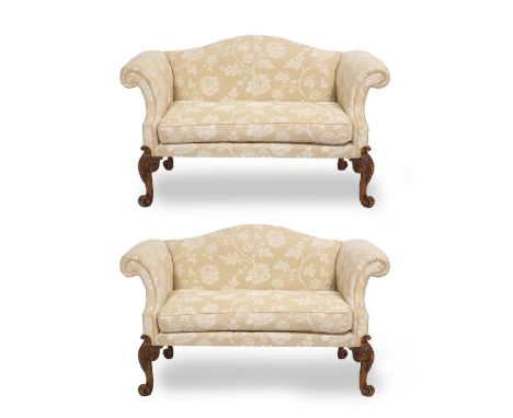 A PAIR OF GEORGE III STYLE CAMEL BACK SOFAS with scrolling arms and acanthus leaf carved cabriole legs terminating in scroll 