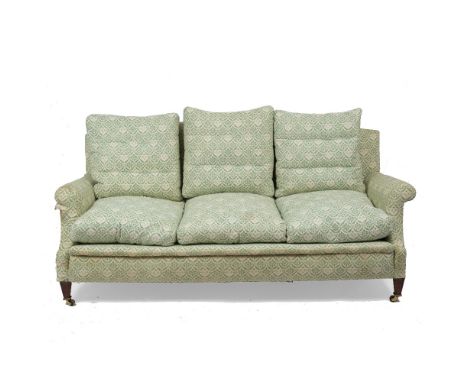 A HOWARD SOFA with arching back and scroll arms with square tapering front legs terminating in brass castors, the back leg st
