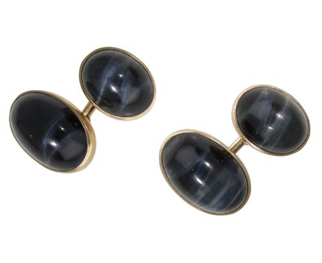 A pair of hawk’s eye cufflinks, the oval panels set with cabochons, gold mounted, stamped ‘9ct’, with chain connectors, panel