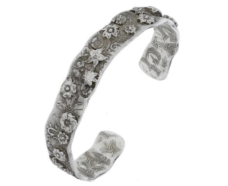 A silver bangle by Malcolm Appleby, struck throughout with flowerheads and foliage, stylised stags and with a dove to either 