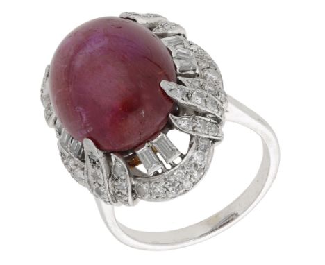 A ruby and diamond dress ring, the ruby cabochon set within a stylised vari-cut diamond surround, total diamond weight approx