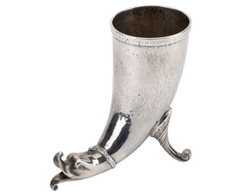A silver drinking horn, 1905, modelled on Viking or Celtic prototypes, the spot-hammered body with dolphin mask terminal and 